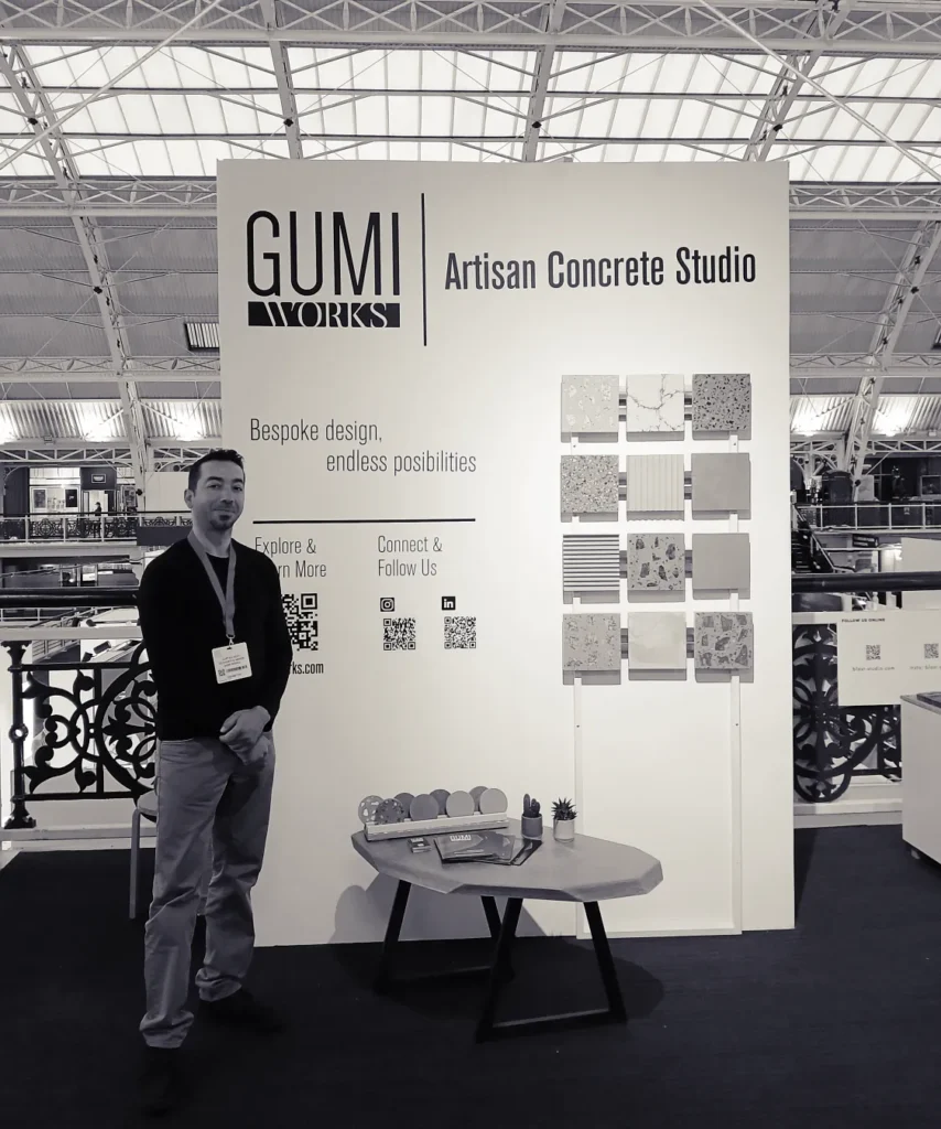 artisan concrete studior -Gumi Works, designer&maker with their custom concrete samples, displayed at surface design show 2025 London. Gumiworks, displaying their new concrete colours, terrazzo finishes, fluted, brass inlay concrete and unique coffee table designs. At display; there is natural marble and granite clippings as aggregates -blended with earthly, 2025 colour trend coloured concrete, 3d textured -fluted, angled concrete samples for wet room applications, furniture and wall panelling as concrete. accent, real metal inlay with concrete veining -an artisanal, high-end furniture concrete finish for refined interiors. İnfo on their services; customisable and bespoke concrete fabricattion for residential and commercial interiors, concrete worktop and tabletops, concrete. dining tables, concrete fireplaces, concrete outdoor kitchens and bbq unit, concrete fireplaces, concrete garden furnitures, concrete basin and vanities for hospitality and residential projects. London based concrete studio -working with interior designers, architects, and private clients for bespoke concrete fabrication service.