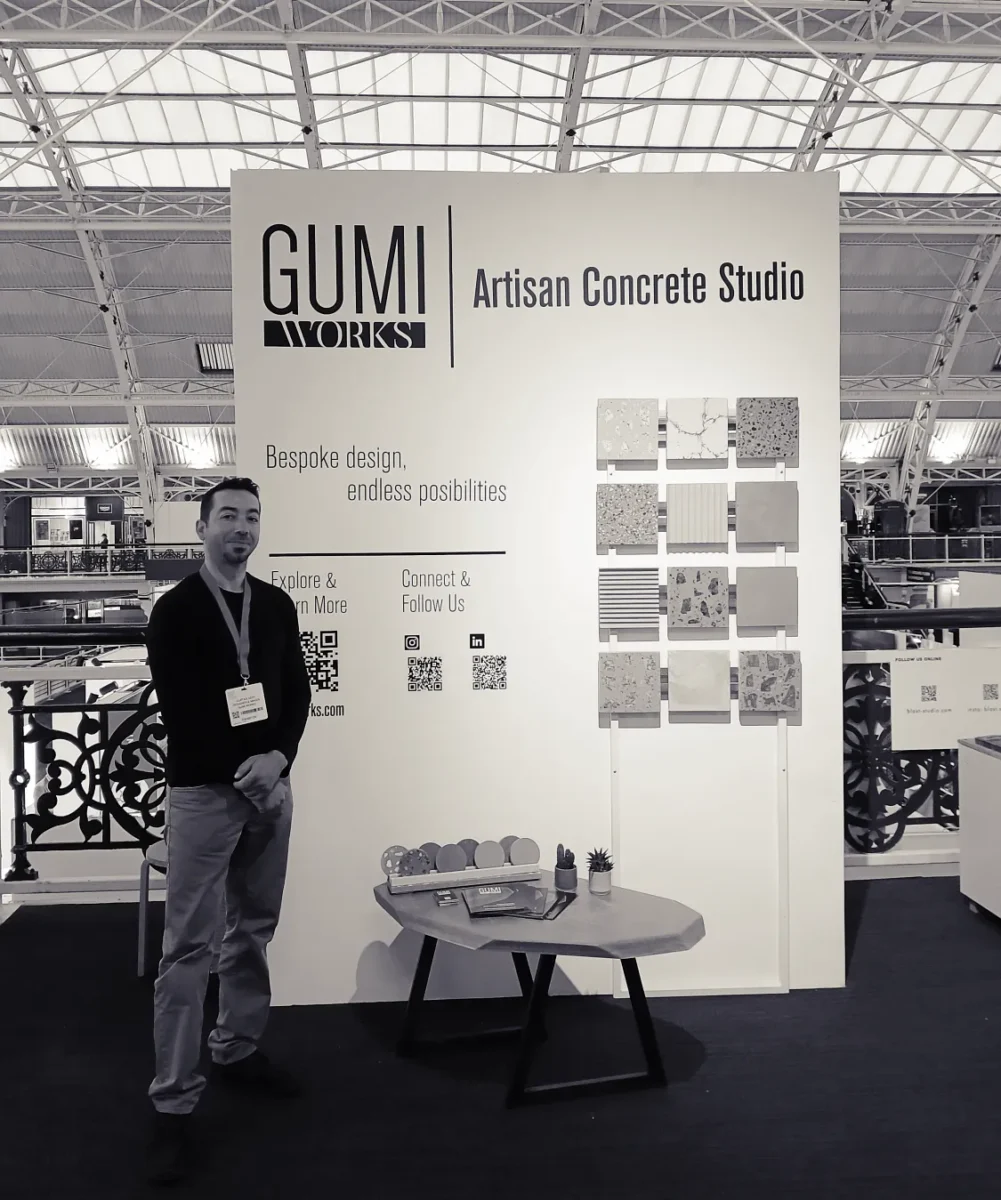 Gumi Works founder at the Surface Design Show London, showcasing bespoke concrete samples, fluted textures, and a custom coffee table for luxury UK interiors.