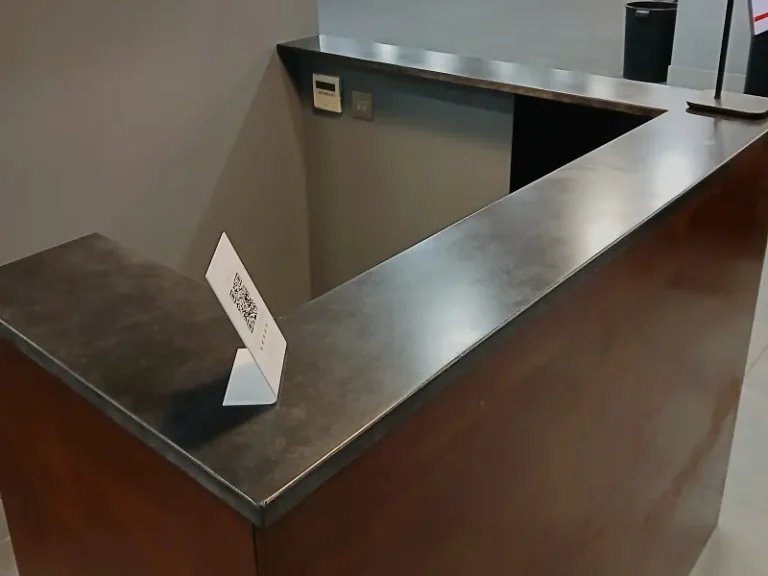 High-angle view of a 25mm thick bespoke concrete reception counter featuring a monolithic 150x165cm J-shaped design.