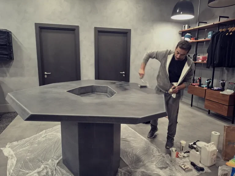 Applying a professional high-performance sealer to a concrete bar table on-site to ensure stain resistance.